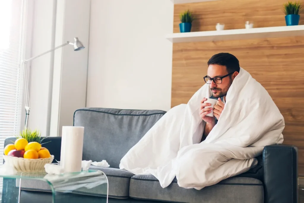 Man wrapped in blanket with tea